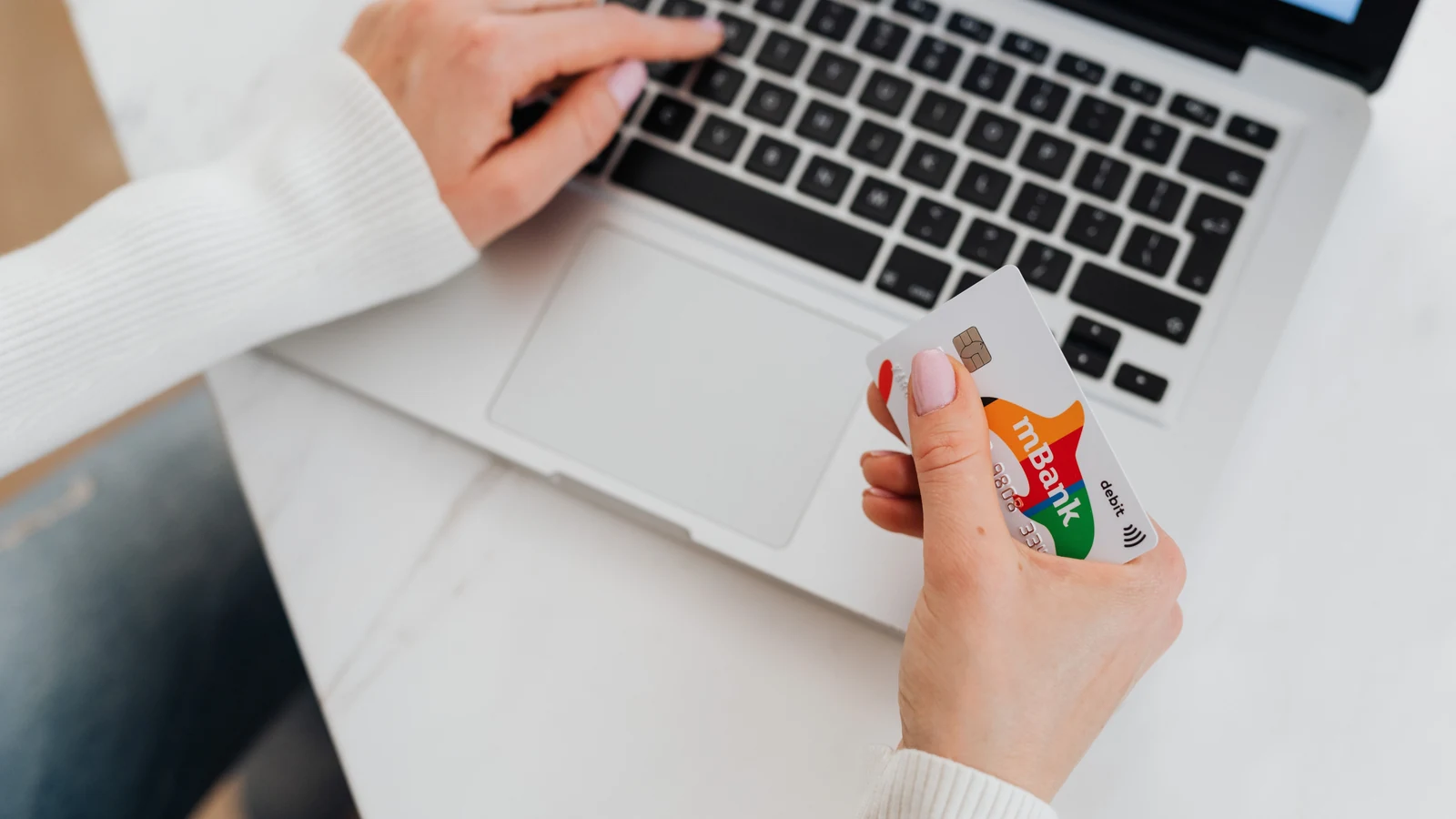 Person holding a bank card while using a laptop