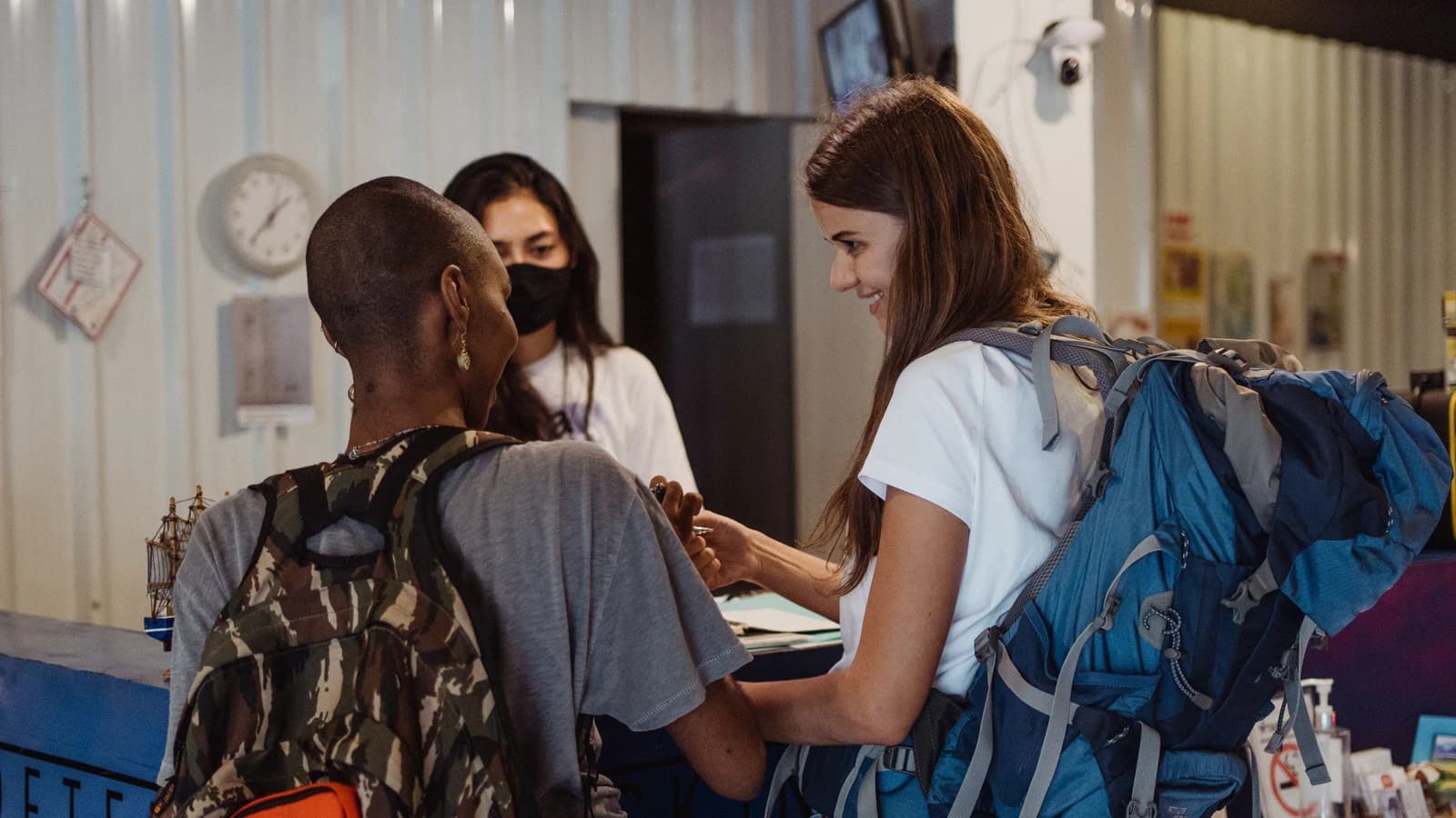 Travelers with backpacks checking in at a hostel reception
