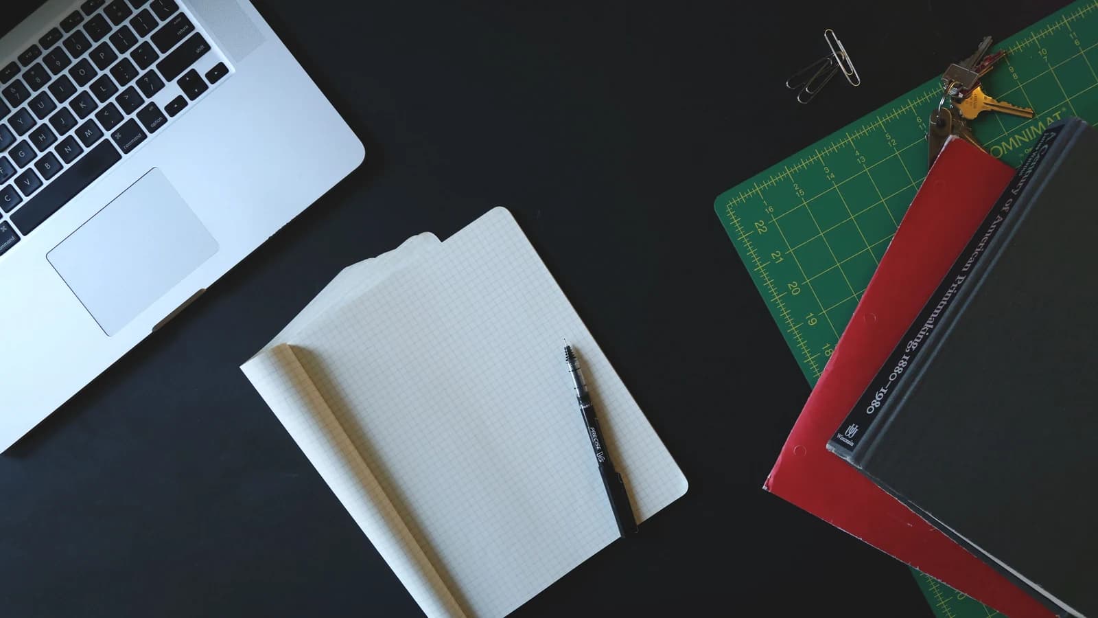Laptop, notebook and office supplies on a dark desk