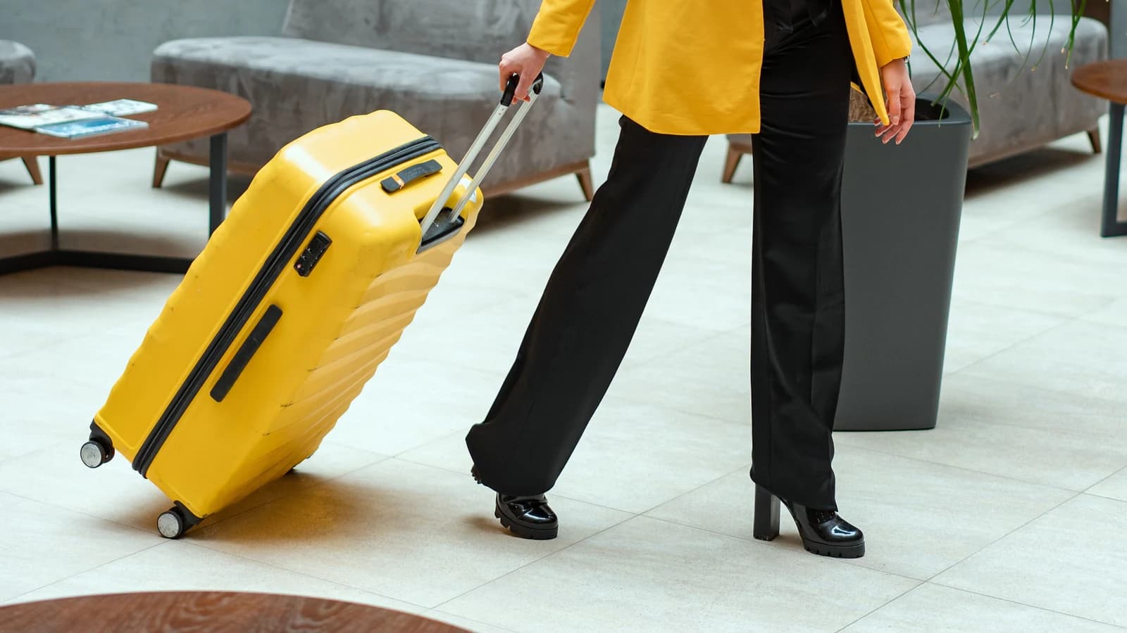 Traveler pulling a bright yellow suitcase through a hotel lobby