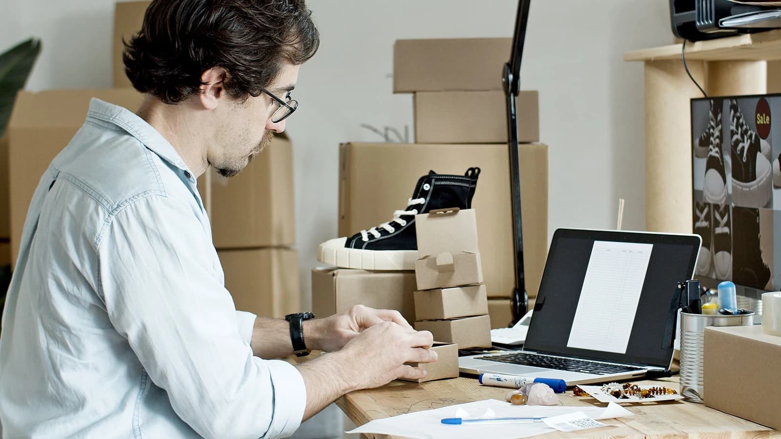 Small-business owner preparing a package beside a laptop