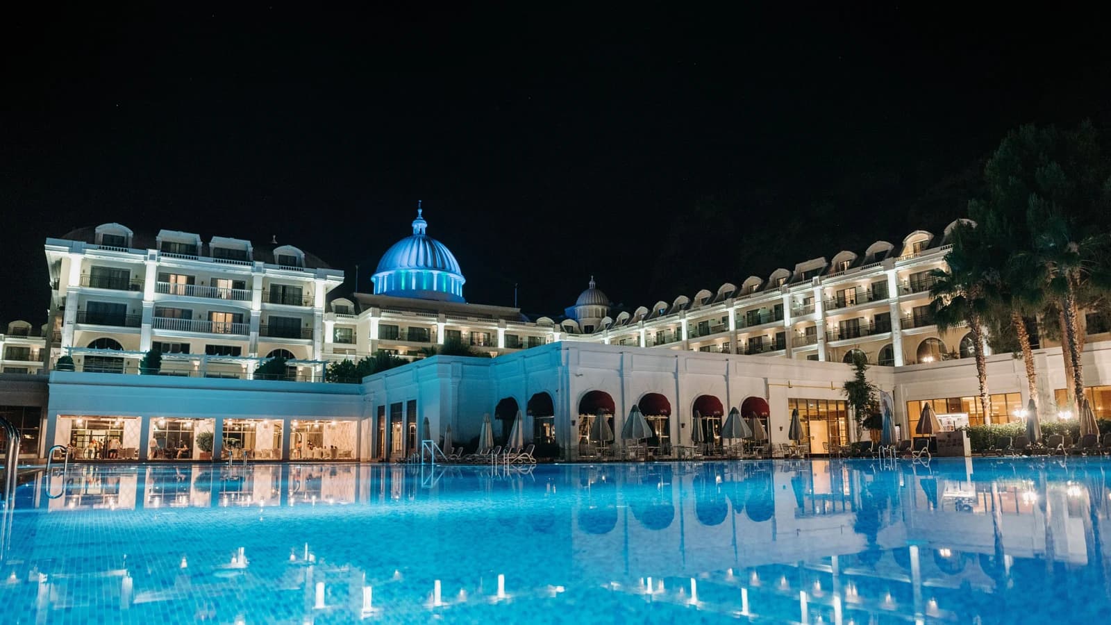 Blue-lit hotel swimming pool and domed building at night