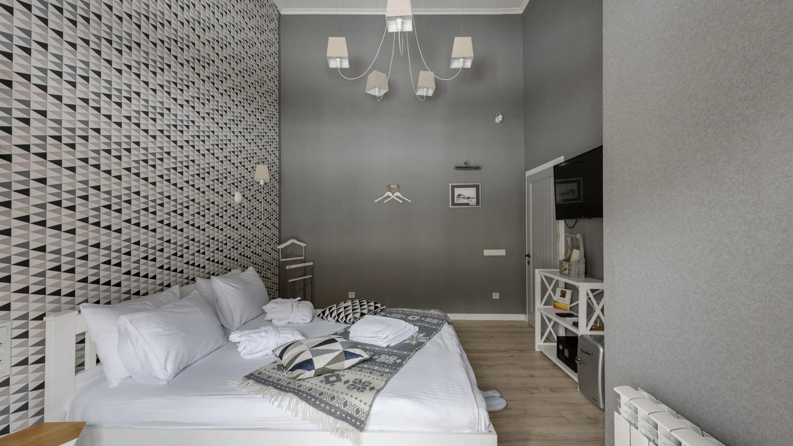 Gray and white hotel bedroom with geometric wallpaper