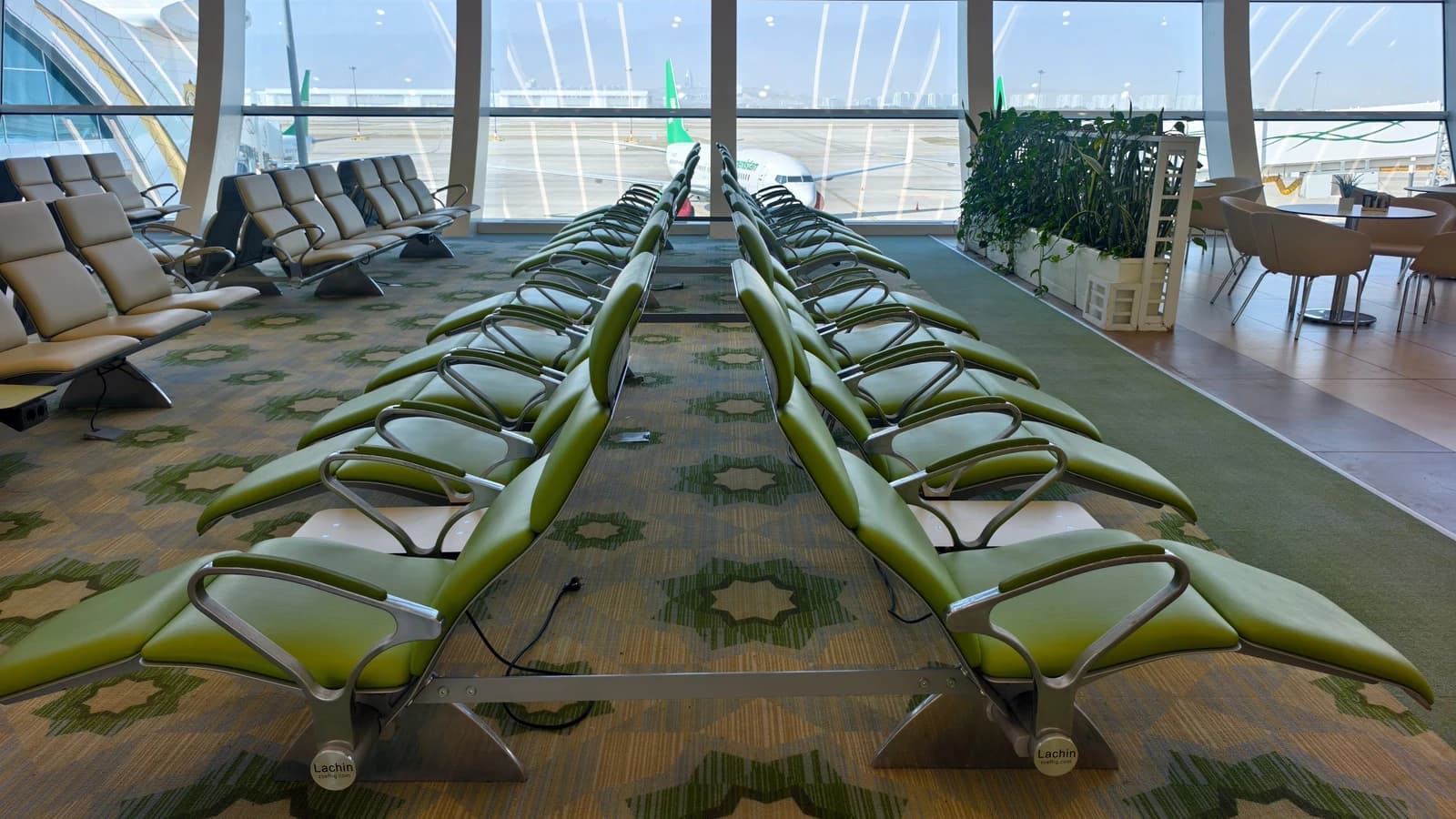 Airport waiting area with green seats and large windows