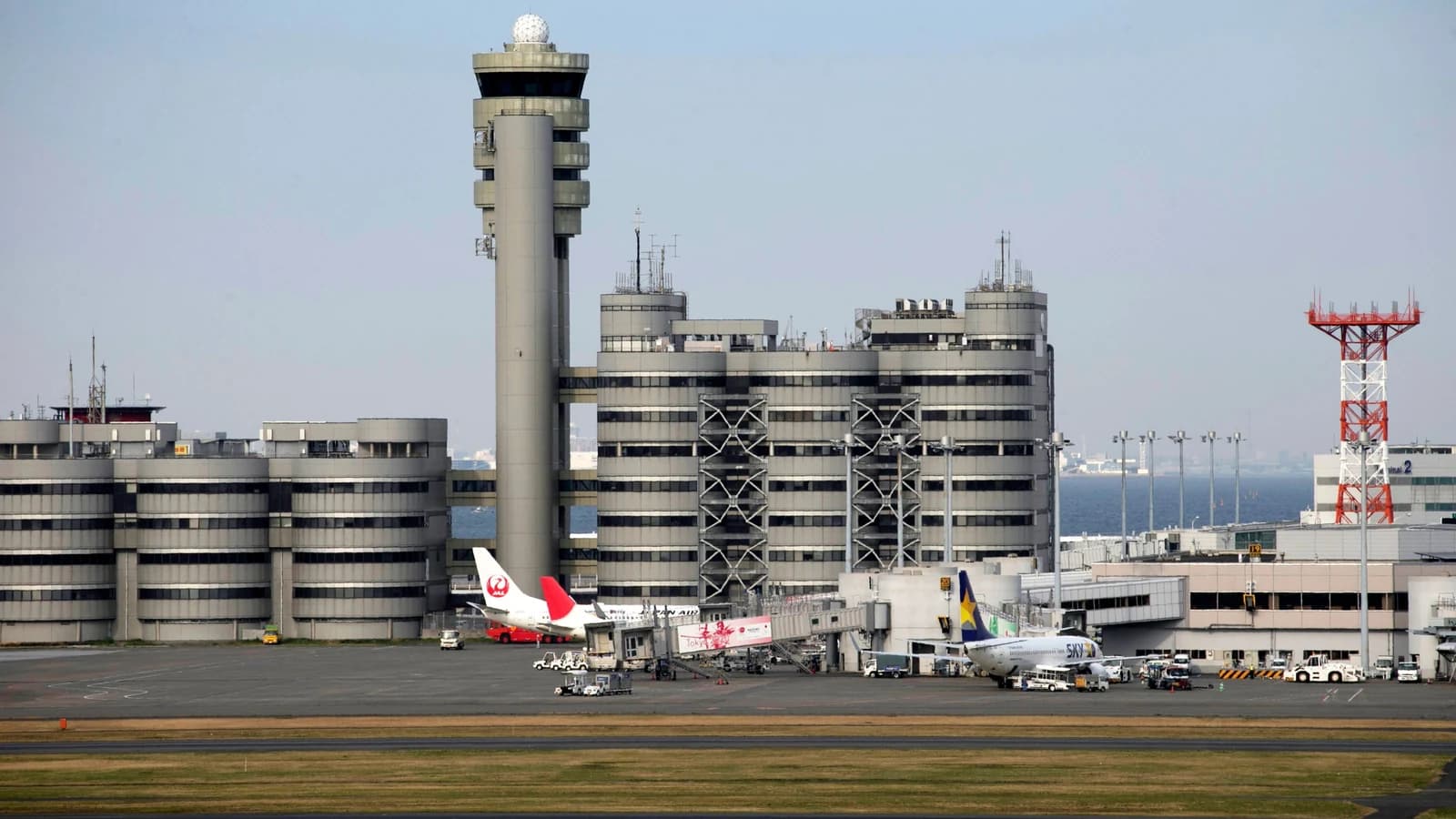 Haneda Airport terminal and control tower with parked aircraft, including a visible Japan Airlines plane