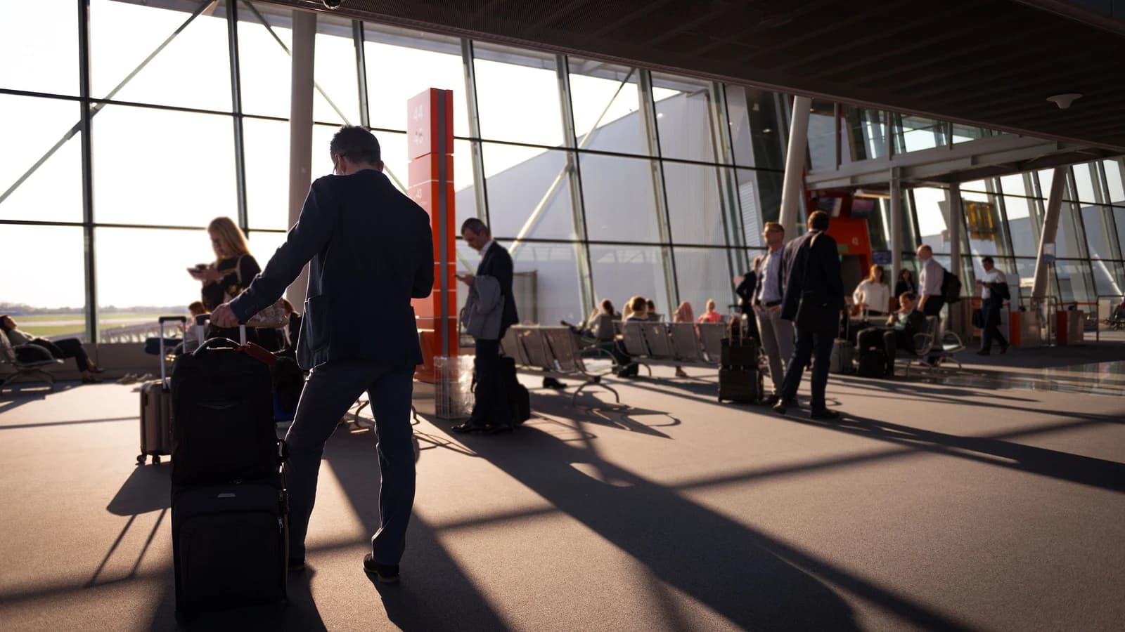 Travelers with carry-on luggage waiting inside a busy airport terminal