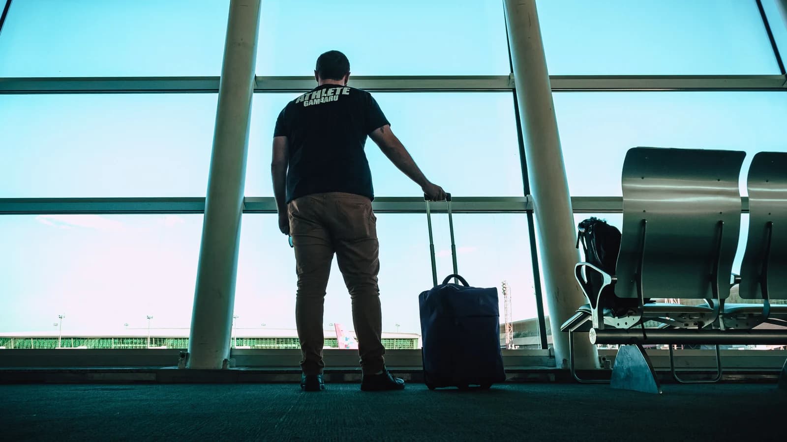 Traveler with luggage waiting near an airport window