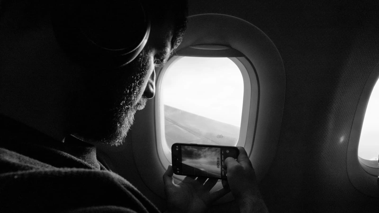 Traveler photographing an airplane wing from a window seat