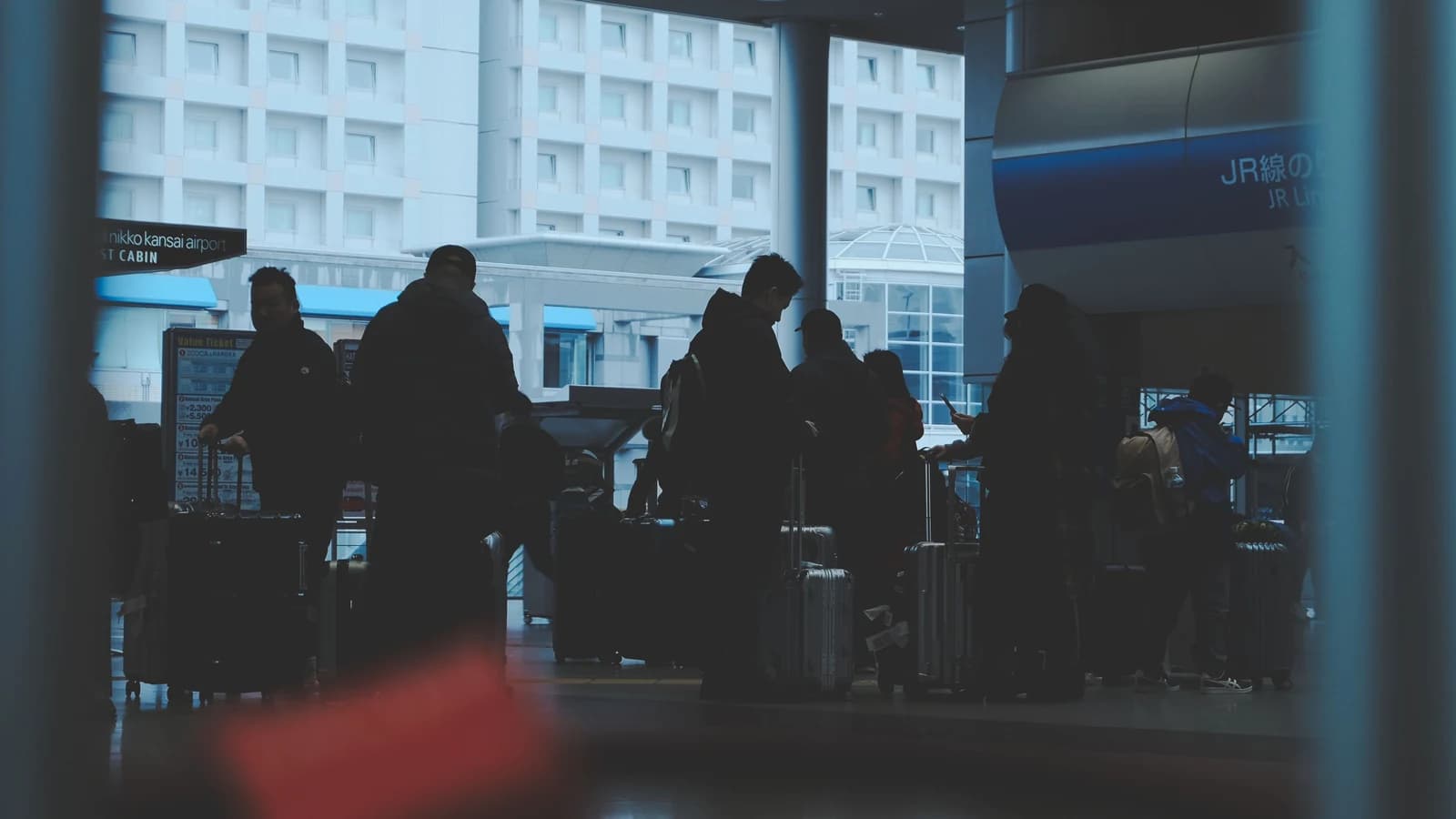 Silhouetted travelers with luggage waiting in a Japanese railway station