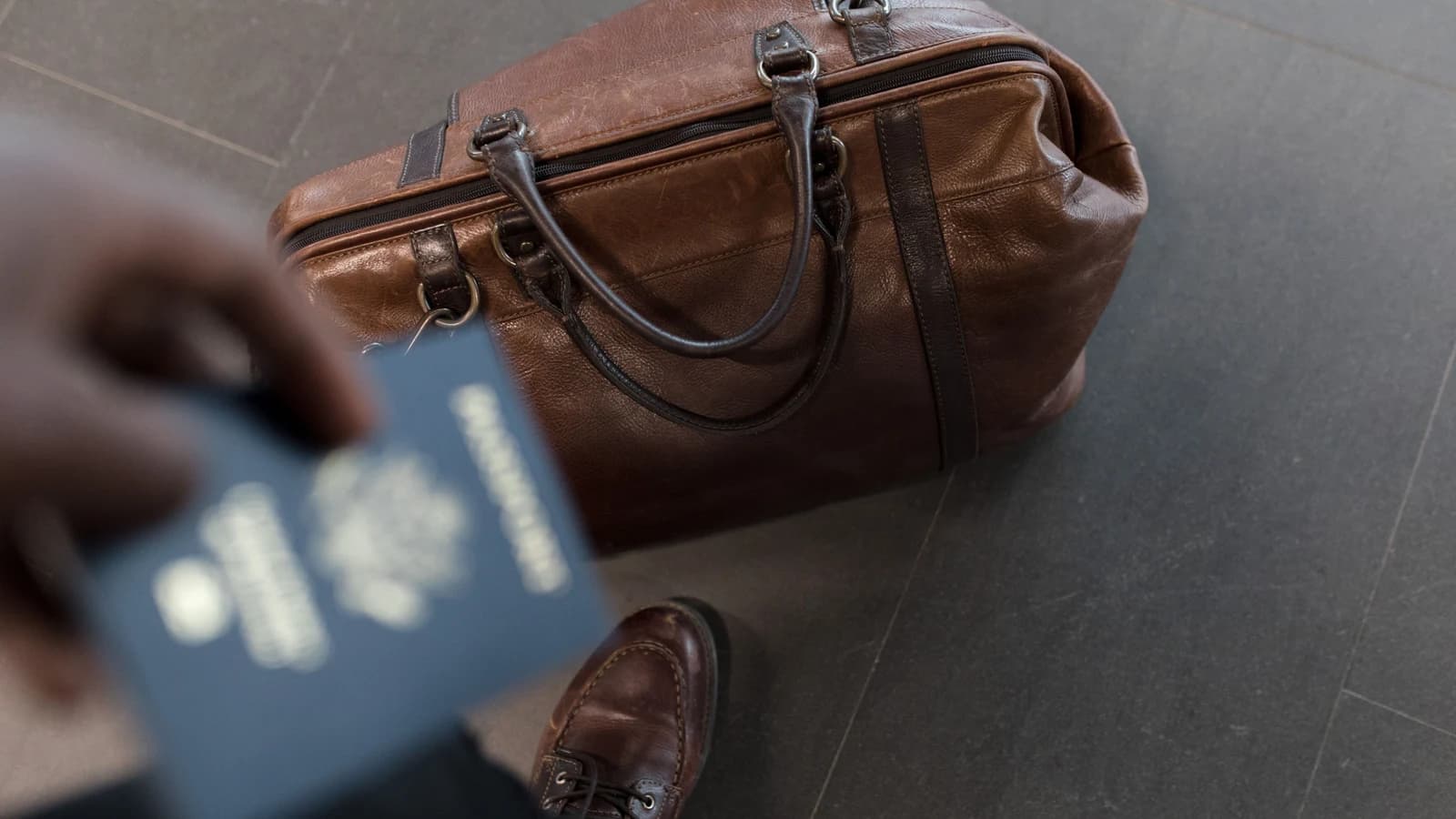 Brown leather carry-on bag with a passport at an airport