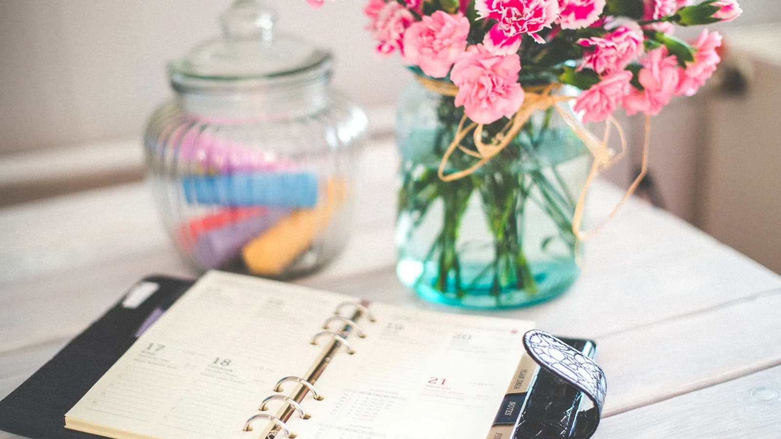 Open personal organizer and pink flowers on a desk
