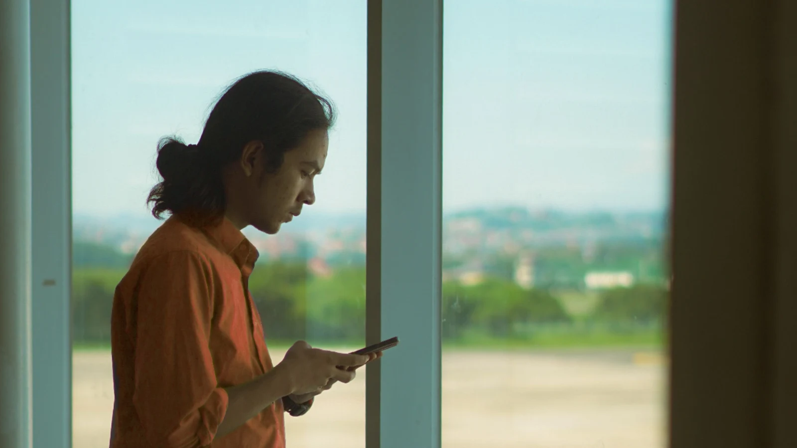 Traveler using a phone at an airport window