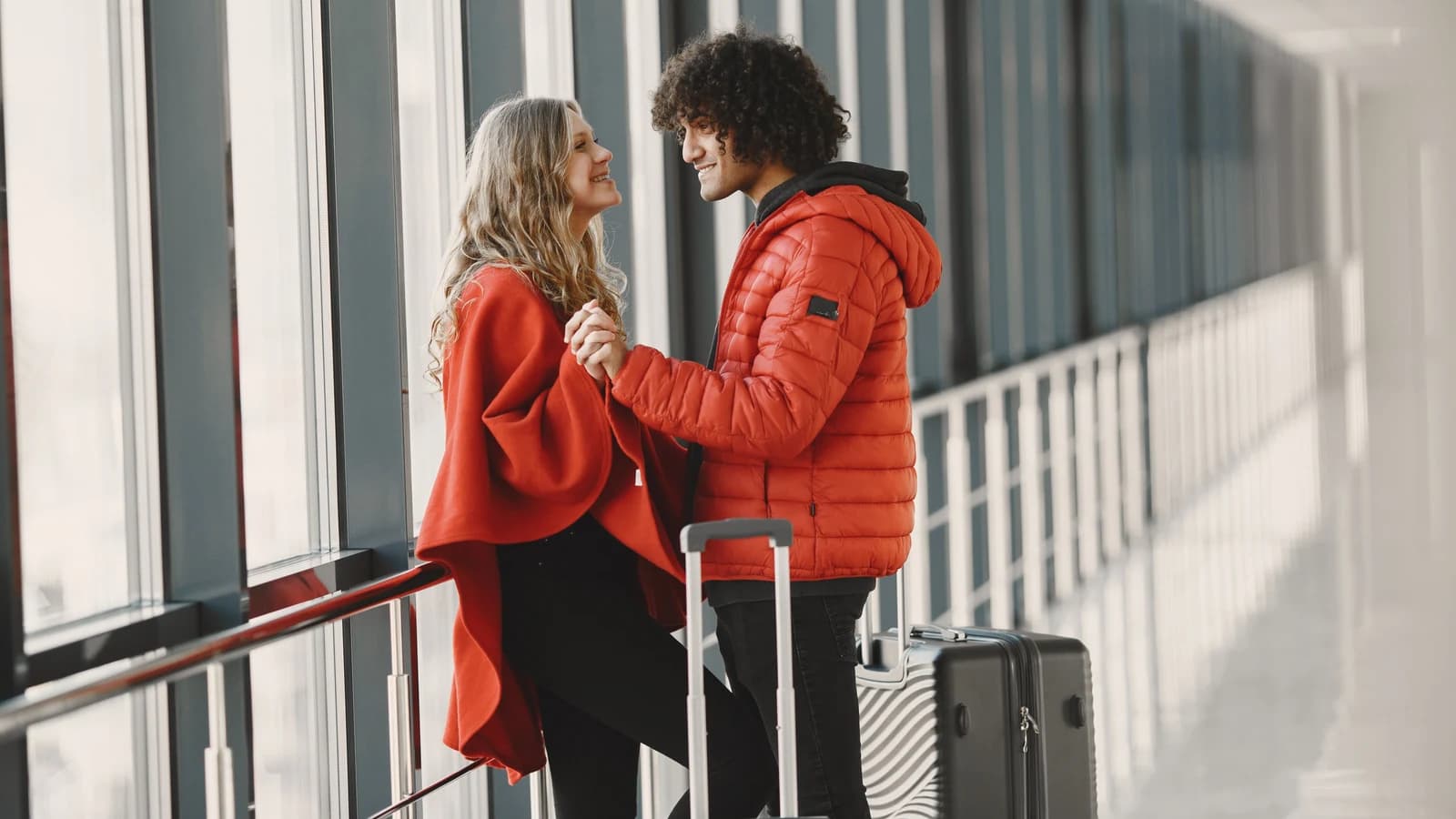 Traveling couple holding hands beside luggage in an airport terminal