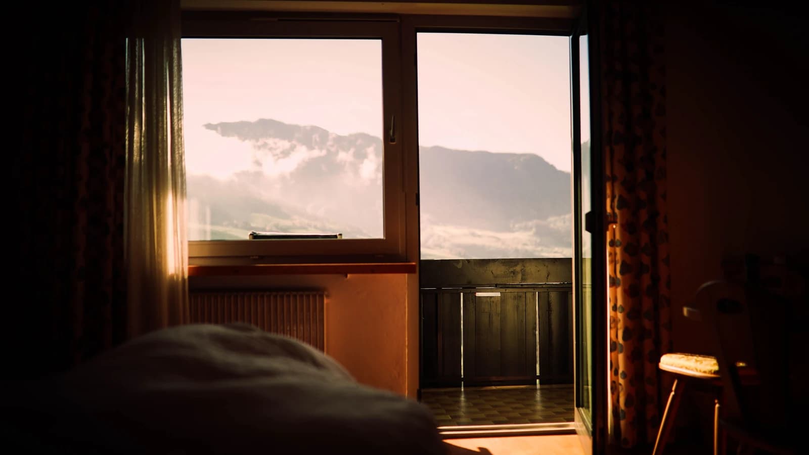 Bedroom with a mountain view through the window at sunset