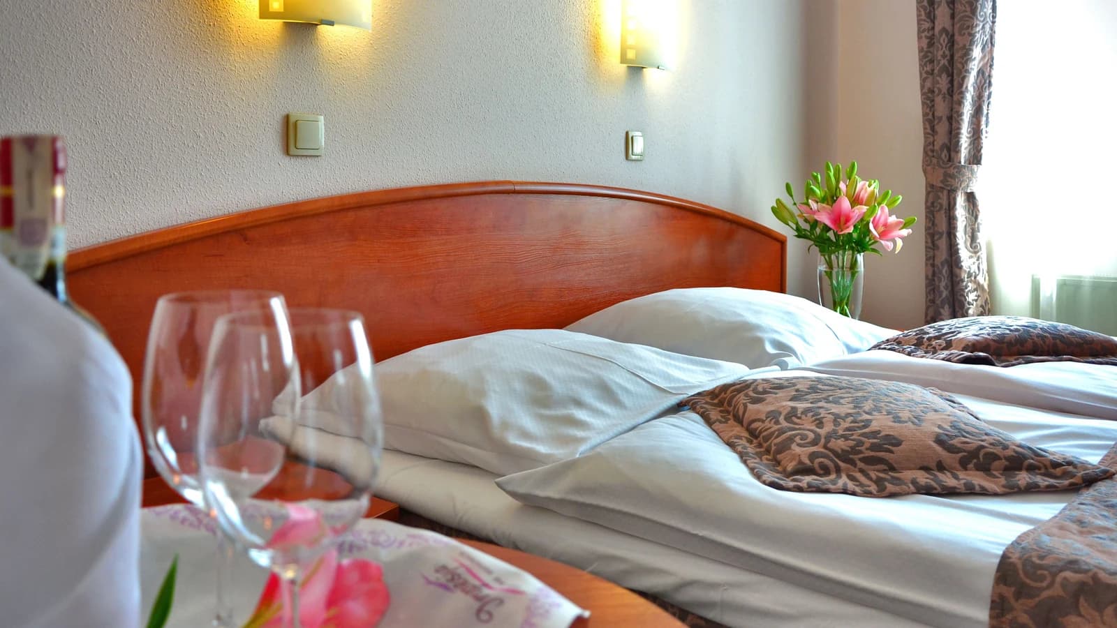 Hotel bedroom with glasses and floral decor on a wooden table