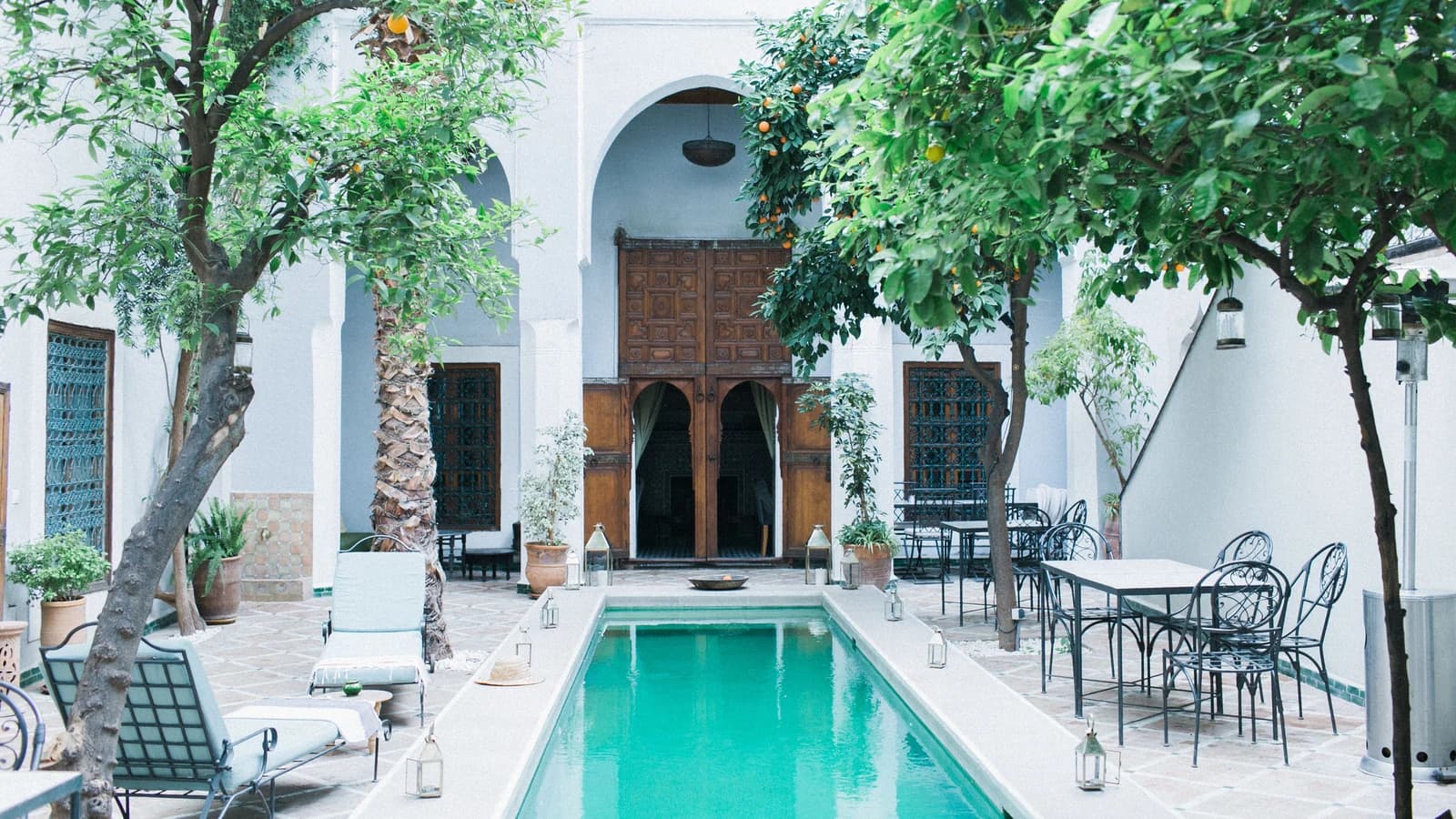 Hotel courtyard with a wooden doorway, tangerine trees and a pool
